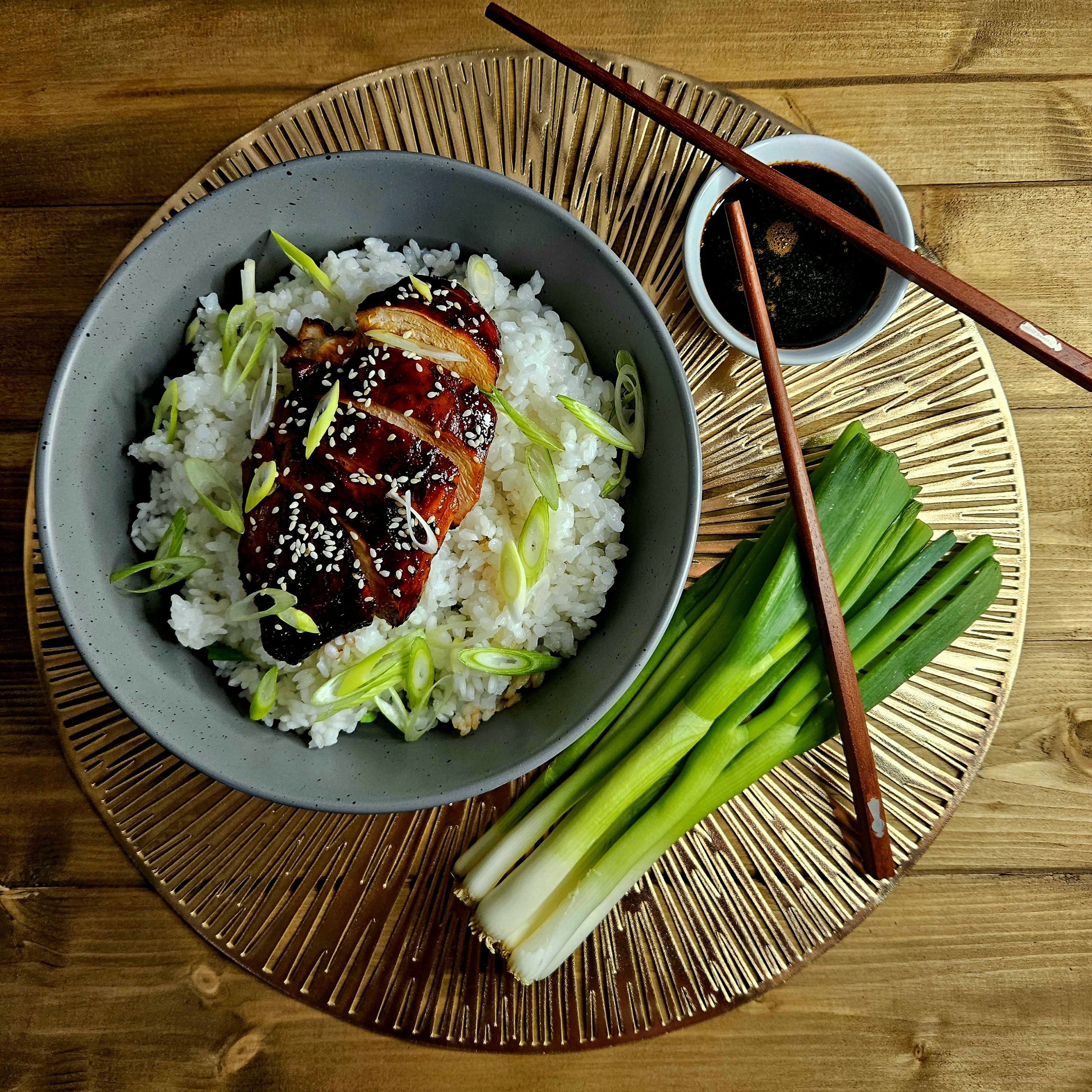 A sticky soy glazed chicken teryaki dish served with jasmine rice and springs onions