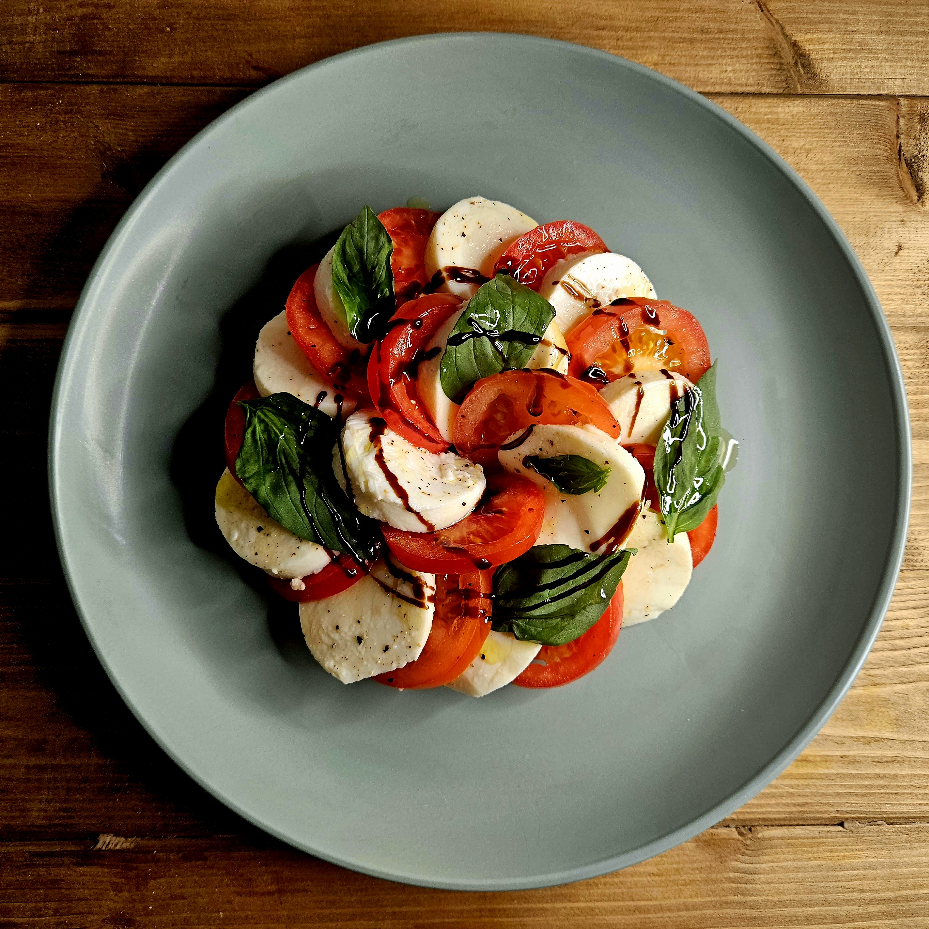 a classic caprese salad consisting of slices of mozzrella, tomatoes and basil and balsamic vinegar.