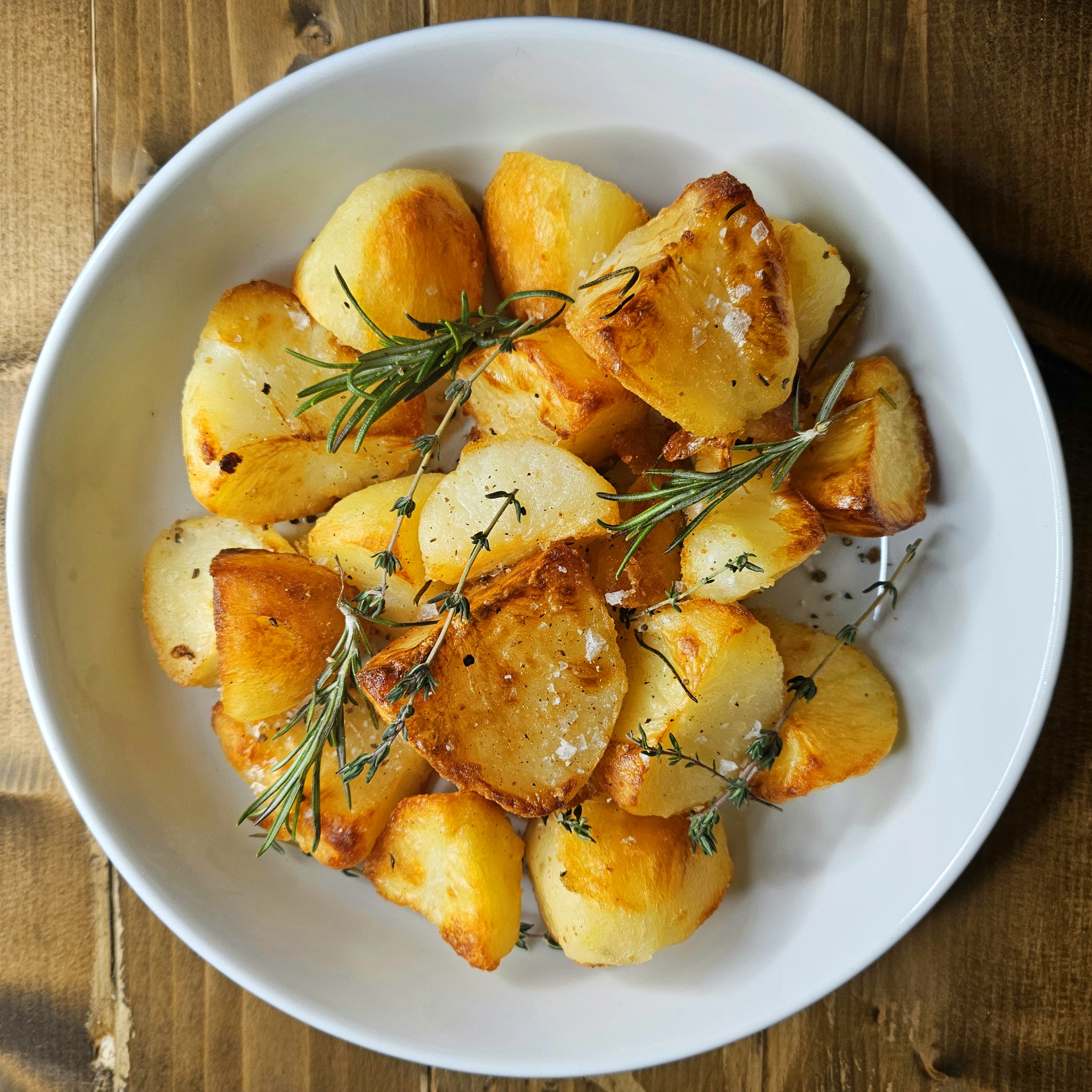 A bowl of perfect roast potatoes with sprogs of thyme